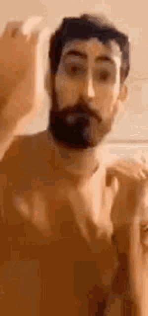 a man with a beard is standing in front of a mirror and looking at himself .