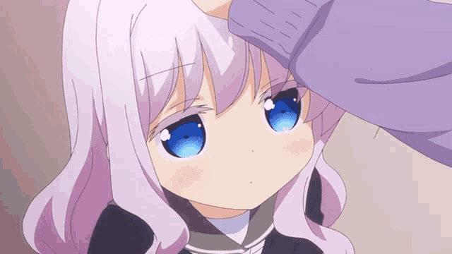 a girl with purple hair and blue eyes is being patted on the forehead by someone
