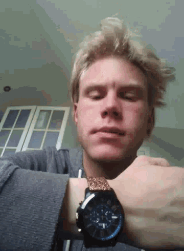 a young man is wearing a watch on his wrist and looking at the time