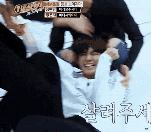 a man is laying on his back while another man holds his head