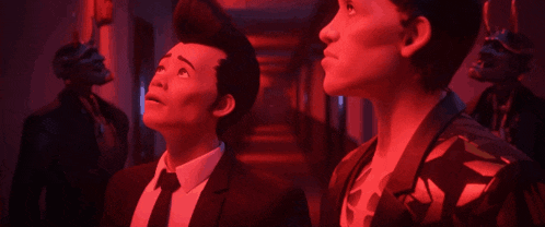 two men in suits and ties are standing in a hallway looking up at something .