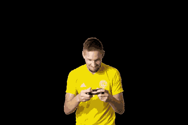 a man in a yellow adidas shirt holds a controller