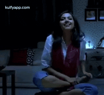 a woman is sitting on the floor with her legs crossed in a living room .