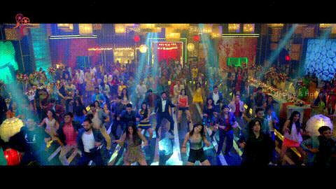 a large group of people are dancing in a room with a sign that says ' bollywood ' on it