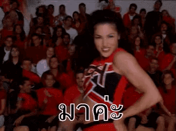 a cheerleader covering her mouth with her hand in front of a crowd of people .