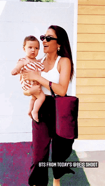 a woman holding a baby with the words bts from today 's @beis shoot below