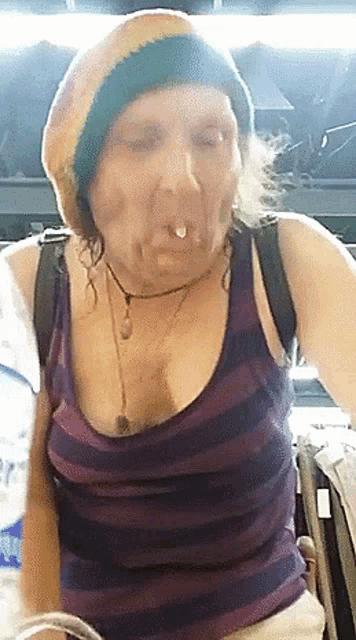 a woman wearing a striped tank top and a rainbow beanie