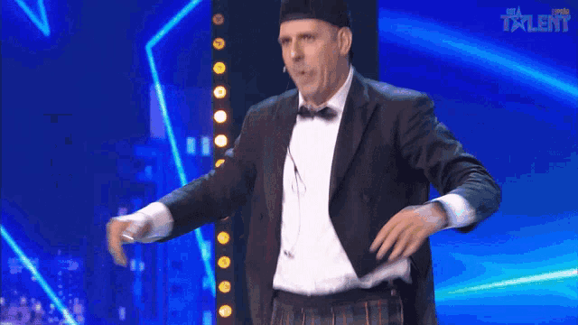 a man in a tuxedo and beret is dancing on a stage with the word talent in the corner