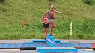 two women are standing next to each other on a wooden bridge .