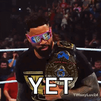 a wrestler wearing pink sunglasses and holding a championship belt says yet