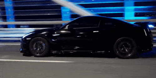 a black sports car is driving down a street