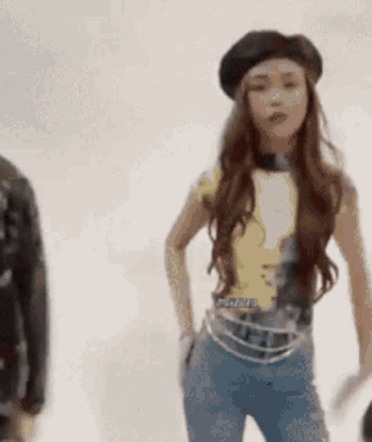 a woman wearing a beret and a yellow shirt is standing with her hands in her pockets .