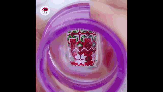 a close up of a person 's nails being painted with a purple stamper .