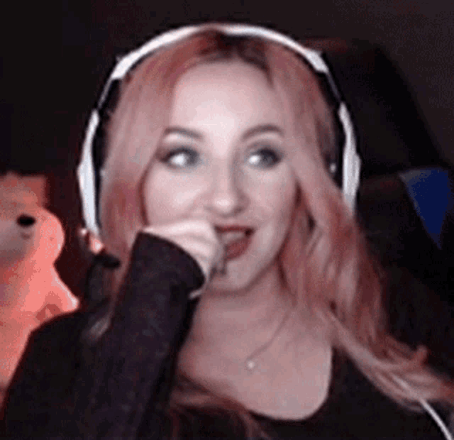 a woman with pink hair wearing headphones and a microphone .