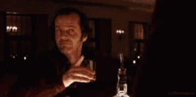 a man is drinking a glass of whiskey in a dark room .