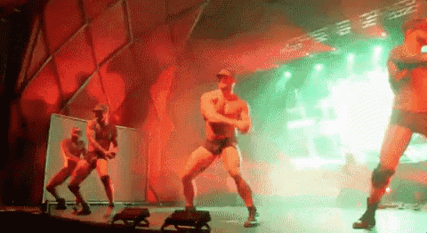 a group of men are dancing on a stage in a club .