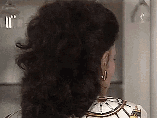 the back of a woman 's head with a steering wheel necklace