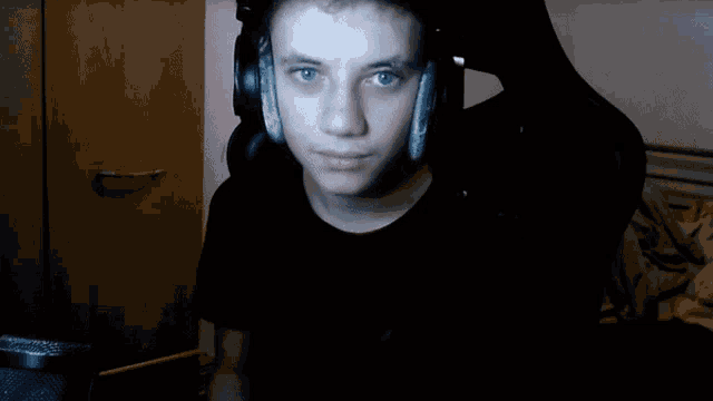 a young man wearing headphones and a black shirt is smiling