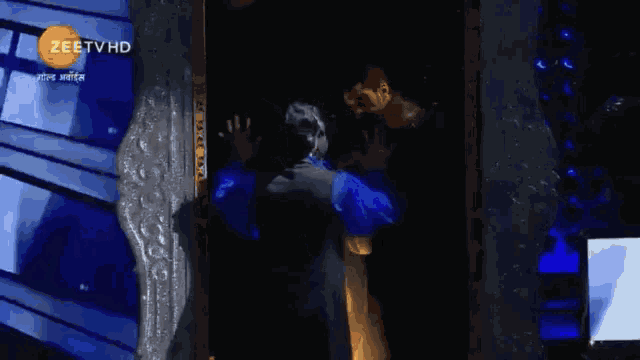 a man is hugging another man in front of a screen that says zeetvhd on it