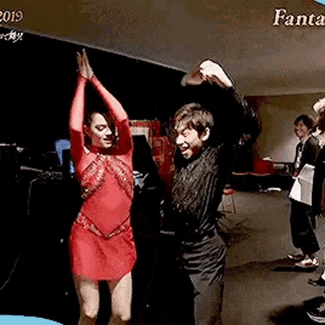 a man and a woman are dancing in a room with their arms in the air .