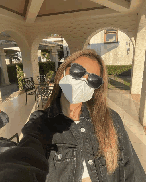 a woman wearing a mask and sunglasses is taking a selfie