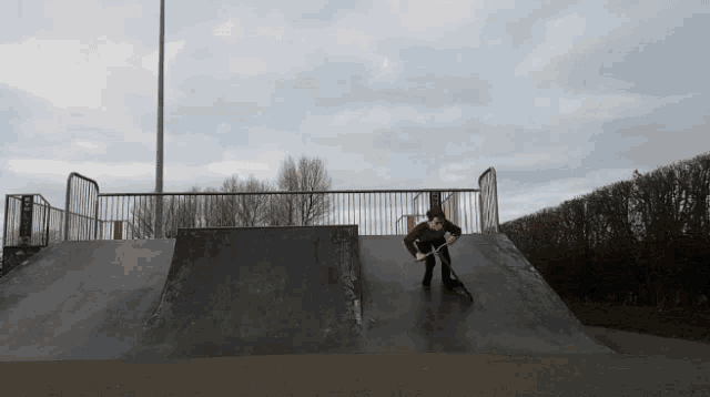 a person is riding a scooter down a ramp at a skate park