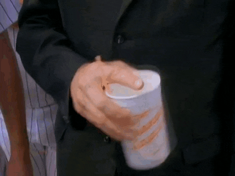 a man in a suit is holding a cup of coffee in his hands .