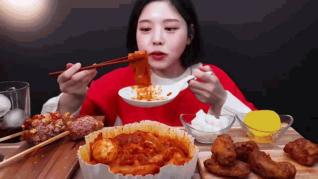 a woman is eating food with chopsticks and a spoon