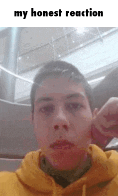 a man in a yellow hoodie is making a funny face with his hand .