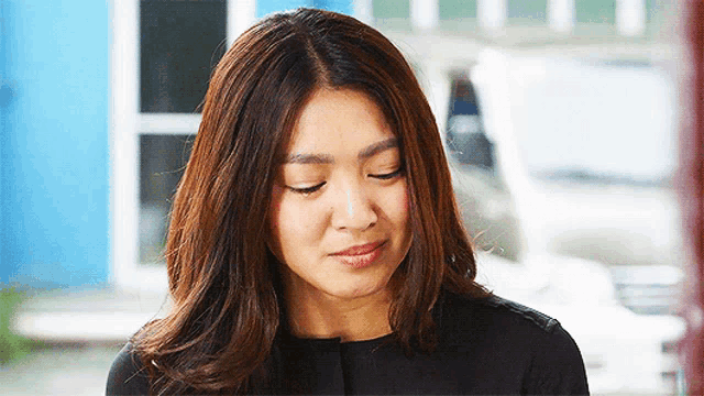 a woman with long brown hair looks down at something