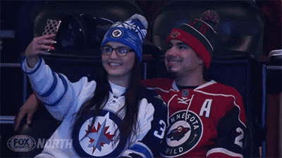 a man and a woman are sitting in a stadium taking a selfie together .