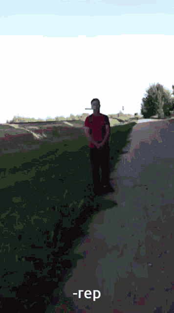 a man in a red shirt is standing on the side of a road with a cigarette in his mouth