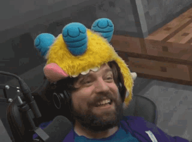 a man with a beard is wearing a stuffed animal hat and headphones