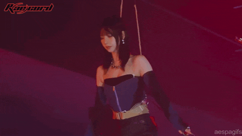 a woman in a black dress is playing a violin in a dark room
