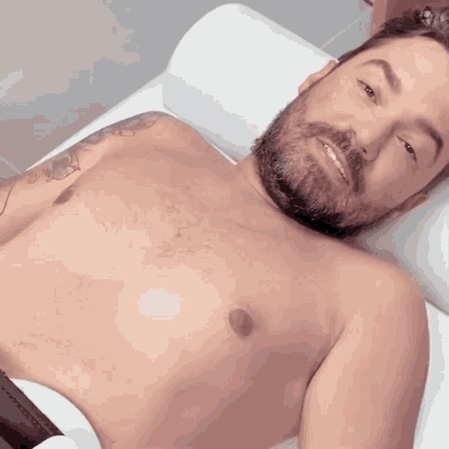 a shirtless man with a beard is smiling
