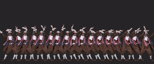 a group of men are standing in a row with their hands up
