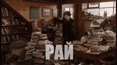 a man is standing in a room filled with lots of books and talking on a cell phone .