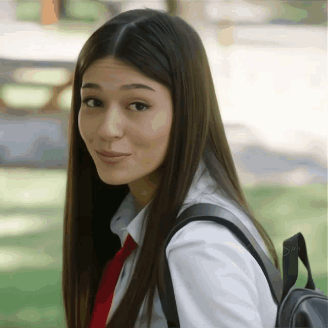 a girl wearing a white shirt and red tie has a backpack