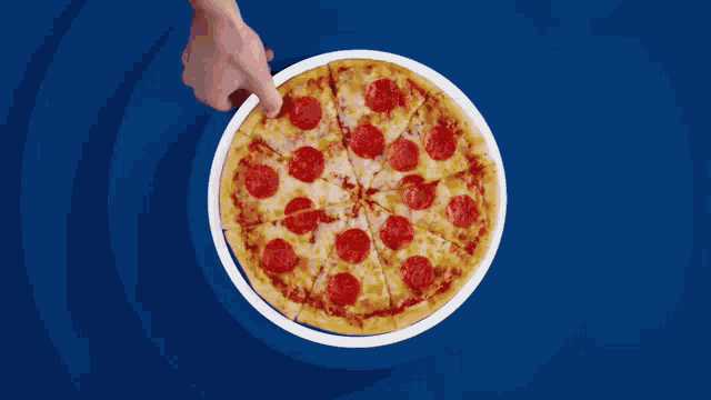 a pepperoni pizza is being cut into slices on a blue and white plate
