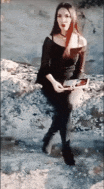 a woman in a black dress holding a book
