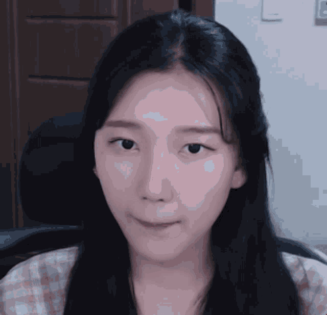 a woman with long black hair is sitting in a chair