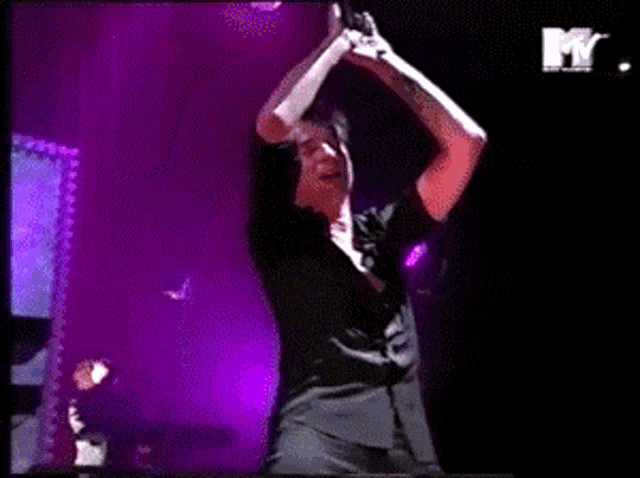 a man in a black shirt is singing into a microphone on a stage