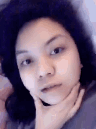 a close up of a woman 's face with a hand on her chin .