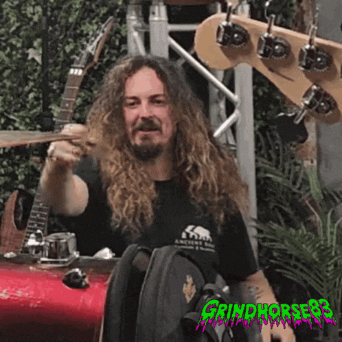 a man with long hair and a beard wearing a black shirt that says grindhorse99
