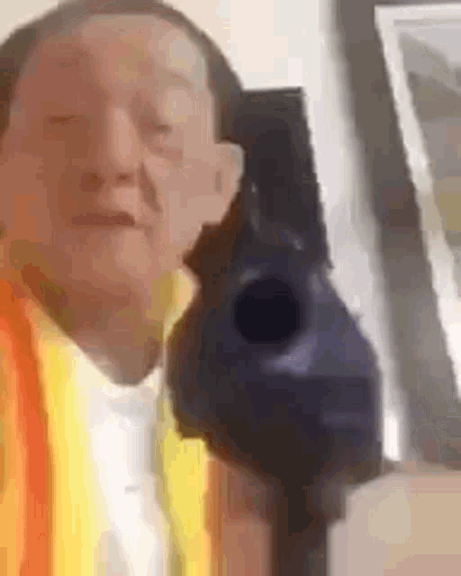 a man is holding a gun in front of his face and taking a selfie .