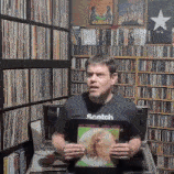 a man wearing a scotch t-shirt is holding a record