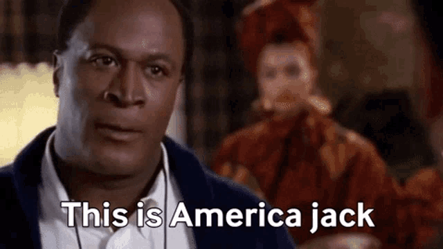 a man in a suit is saying this is america jack in front of a woman in a red dress .