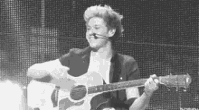 a young man is playing an acoustic guitar on a stage .