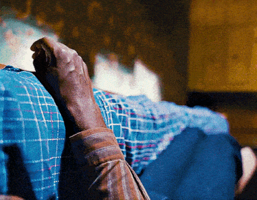 a person laying on a bed with a blue plaid shirt