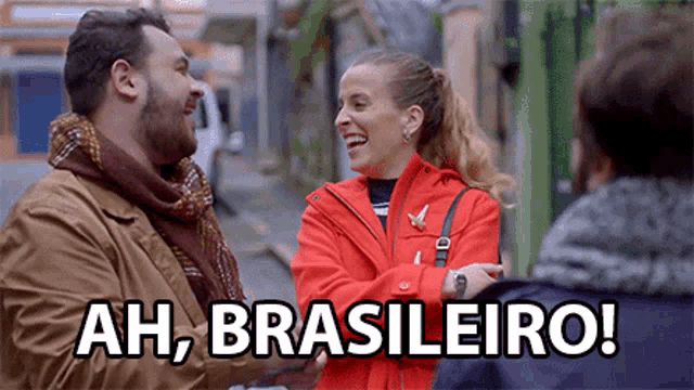 a man and a woman are laughing and the woman is wearing a red jacket with the words ah brasileiro on it